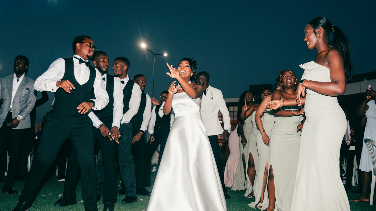 A bride dancing with her bridesmaids and groomsmen at a night reception
